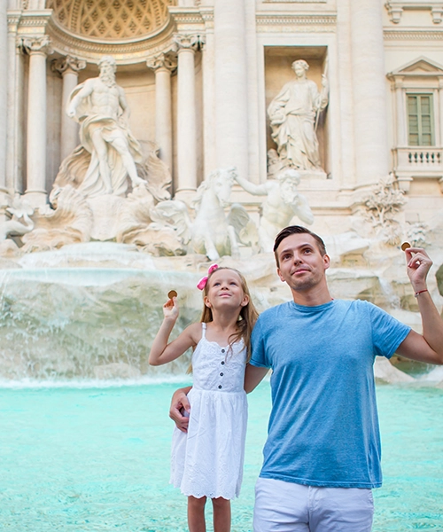 Un padre con su hija tirando una moneda en la Fontana de Trevi. Viaje especial a Roma organizado por Caramelo Tours.